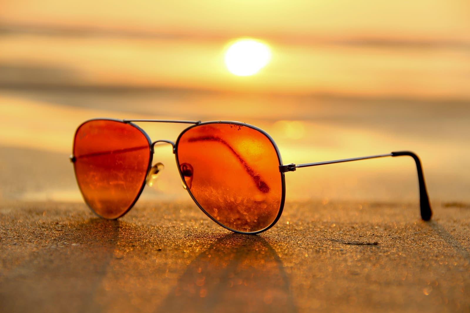 Polarized sunglasses resting on sand in warm coastal light
